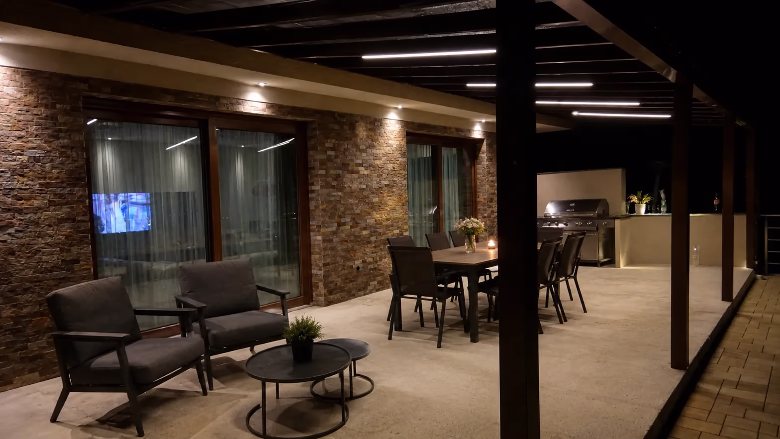 Fa pergola integrált LED-szalag világítással egy éjszakai, étkezőasztalos terasz felett