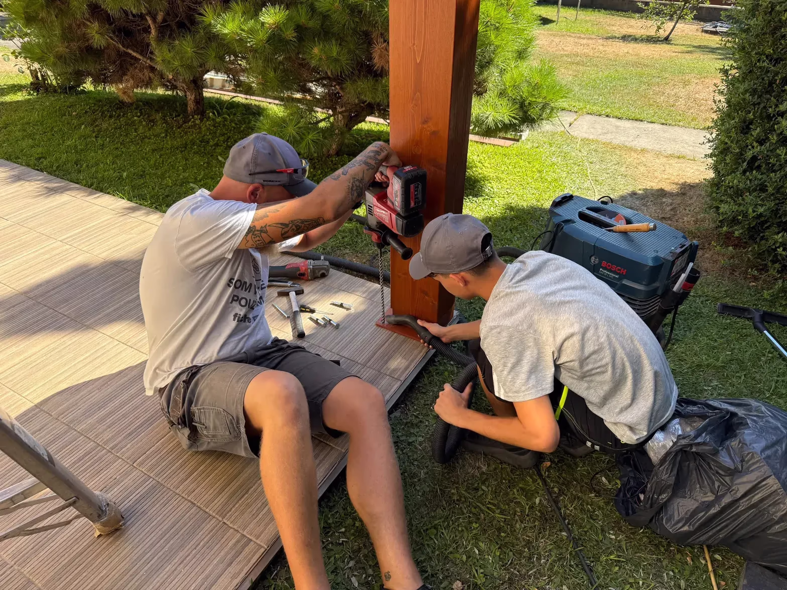 Szerelők rögzítőfuratokat fúrnak egy fa pergola tartóoszlopába